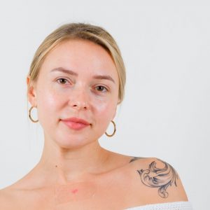 Portrait of blonde lady pointing to the right side in cardigan and looking confident front view